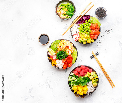 Poke bowl set: tuna, salmon, shrimps with avocado, fruits and vegetables, white rice and other ingredients. Hawaiian cuisine dish. White table background, top view