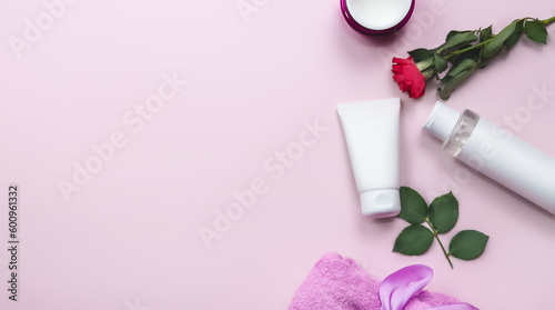Set of skin care products on pink pastel background with roses flowers. Skin care concept. Womens day cosmetics