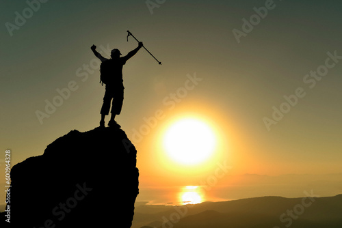 silhouette of professional mountaineer achieving summit achievement at magnificent sunrise