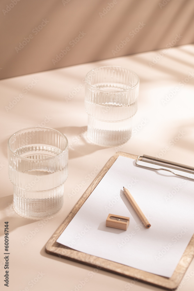 Clipboard, glass of water, light background. Paper. Clipboard, glass of water, light background. Paper.