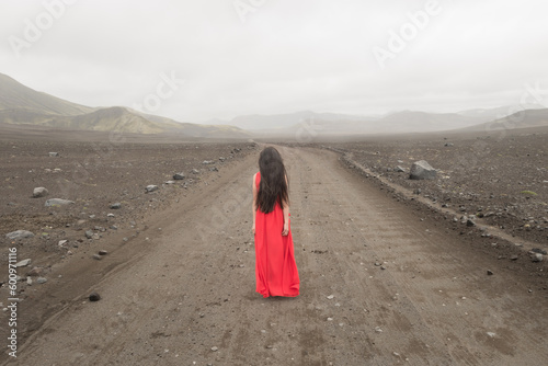 girl in red dress in misty landscape of Iceland on road to nowhere