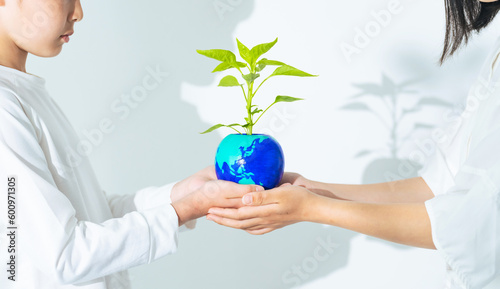 地球の描かれた植木鉢を受け渡す手 環境保護イメージ