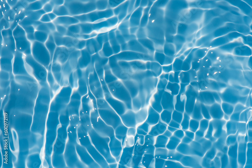 Blue water with ripples on the surface. Defocus blurred transparent blue colored clear calm water surface texture with splashes and bubbles. Water waves with shining pattern texture background.