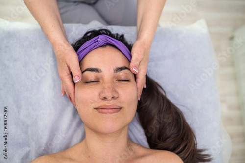 pretty woman getting enjoying facial massage with closed eyes at beauty salon