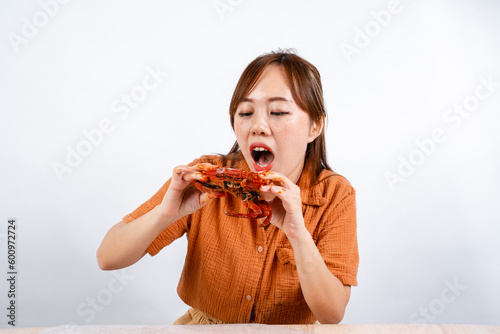 young asian woman enjoys eating seafood, crab with padang sauce (Indonesian : Kepiting Saus Padang) isolated on white background