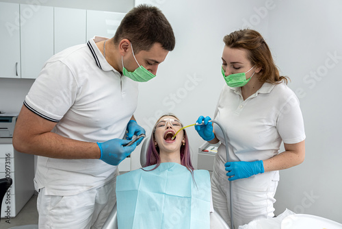 woman has her teeth treated by male dentist female assistant during an appointment