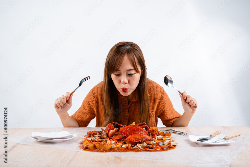 young asian woman enjoys eating seafood, crab with padang sauce (Indonesian : Kepiting Saus Padang) isolated on white background young asian woman enjoys eating seafood, crab with padang sauce (Indonesian : Kepiting Saus Padang) isolated on white background