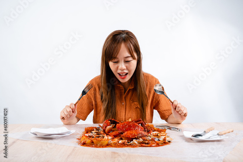 young asian woman enjoys eating seafood  crab with padang sauce  Indonesian   Kepiting Saus Padang  isolated on white background