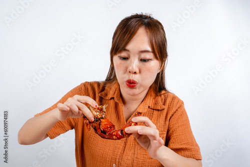 young asian woman enjoys eating seafood, crab with padang sauce (Indonesian : Kepiting Saus Padang) isolated on white background