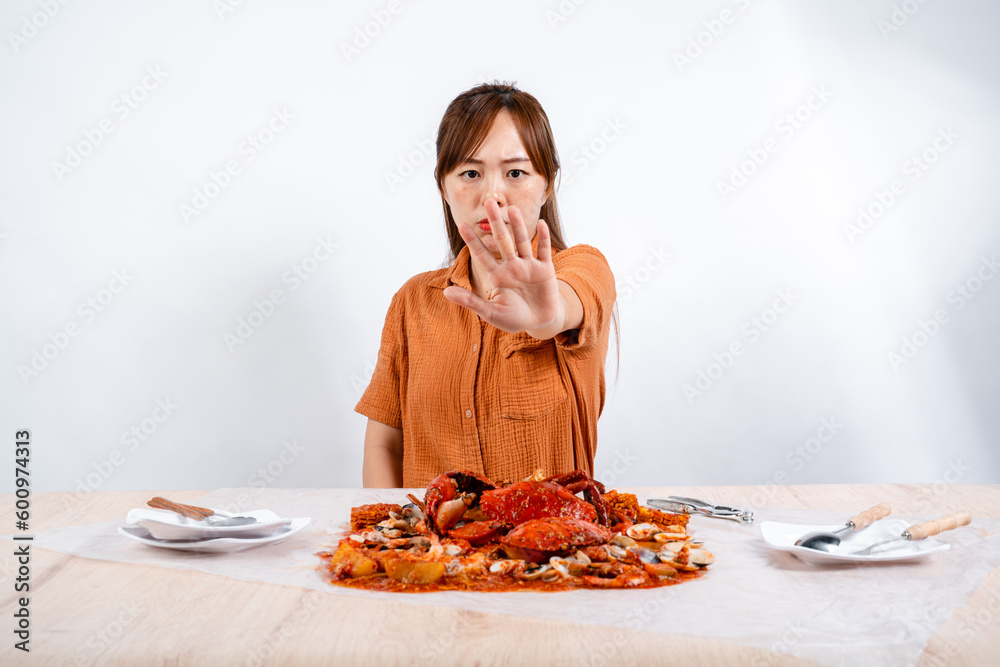 Young Asian woman say no to eating seafood, crab with padang sauce (Indonesian : Kepiting Saus Padang) isolated on white background