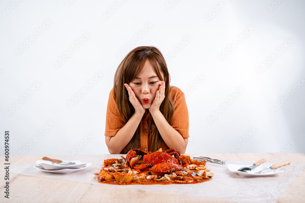 young asian woman enjoys eating seafood, crab with padang sauce (Indonesian : Kepiting Saus Padang) isolated on white background young asian woman enjoys eating seafood, crab with padang sauce (Indonesian : Kepiting Saus Padang) isolated on white background