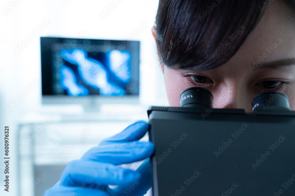 Asian female researcher working with a microscope in a laboratory. Asian female researcher working with a microscope in a laboratory.