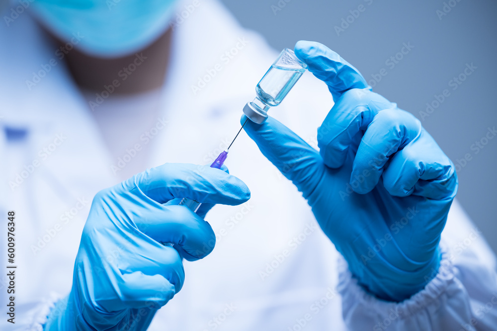 Doctor hand in blue gloves holding influenza vaccine for prevention human.Concept fight against human papilloma virus, nurse in laboratory holding a syringe with HPV vaccines for girl and woman. Doctor hand in blue gloves holding influenza vaccine for prevention human.Concept fight against human papilloma virus, nurse in laboratory holding a syringe with HPV vaccines for girl and woman.