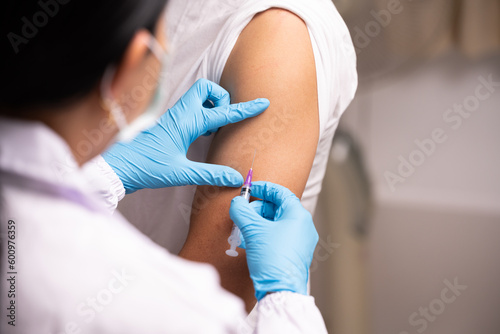 Doctor hand in blue gloves holding influenza vaccine for prevention human.Nurse holding syringe make injection in shoulder of patient in hospital.Covid-19 or coronavirus vaccine.