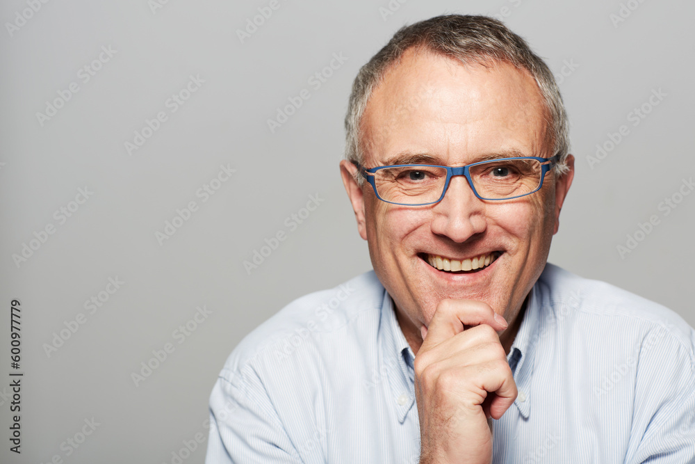 Senior man, portrait and smile in studio with happiness, pride and confident by gray background. Elderly guy, happy and excited face for experience, knowledge and retirement by backdrop with glasses