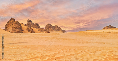 Typical desert landscape in Alula, Saudi Arabia, sand with some mountains, small offroad vehicle, dramatic orange sky above
