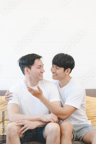 Happy Asian gay couple hug together on sofa. Asian LGBT couple embracing together at home. Diversity of LGBT relationships. A gay couple concept. LGBT multi relationship.