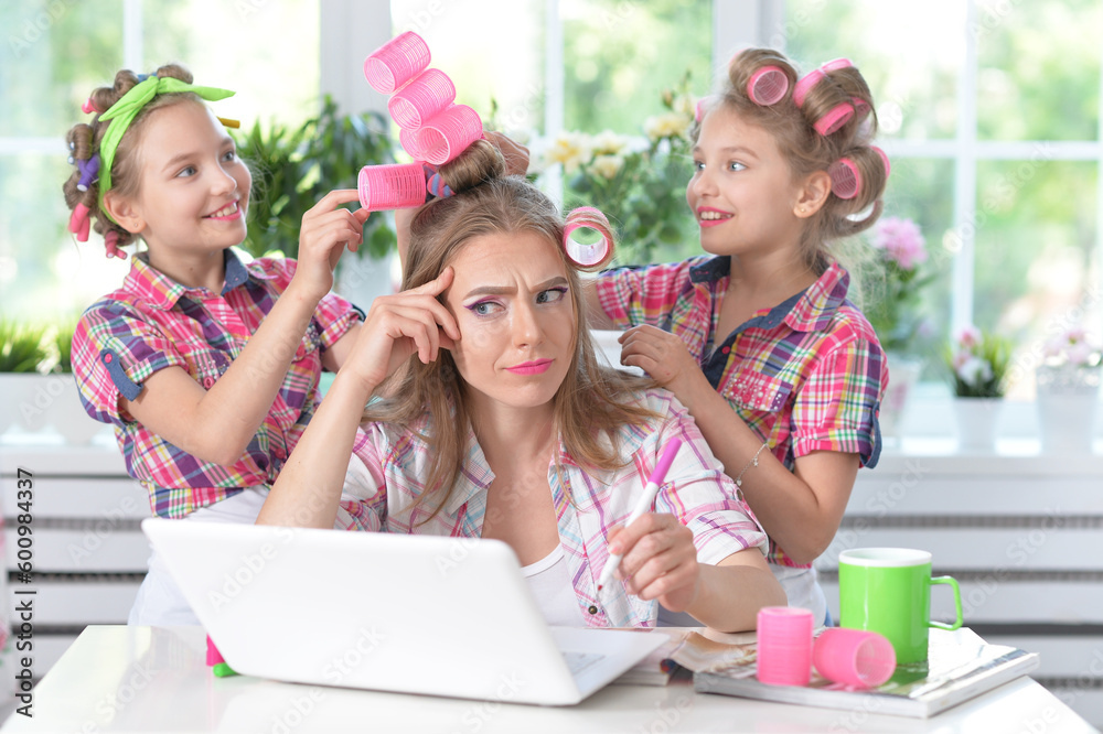 Cute tweenie girls and mother in hair curlers with laptop at home Cute tweenie girls and mother in hair curlers with laptop at home