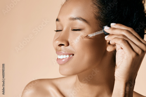 Beautiful woman applying essential oil on her face for hydrated skin using pipette dropper. Facial skin care with treatment essential oil and serum