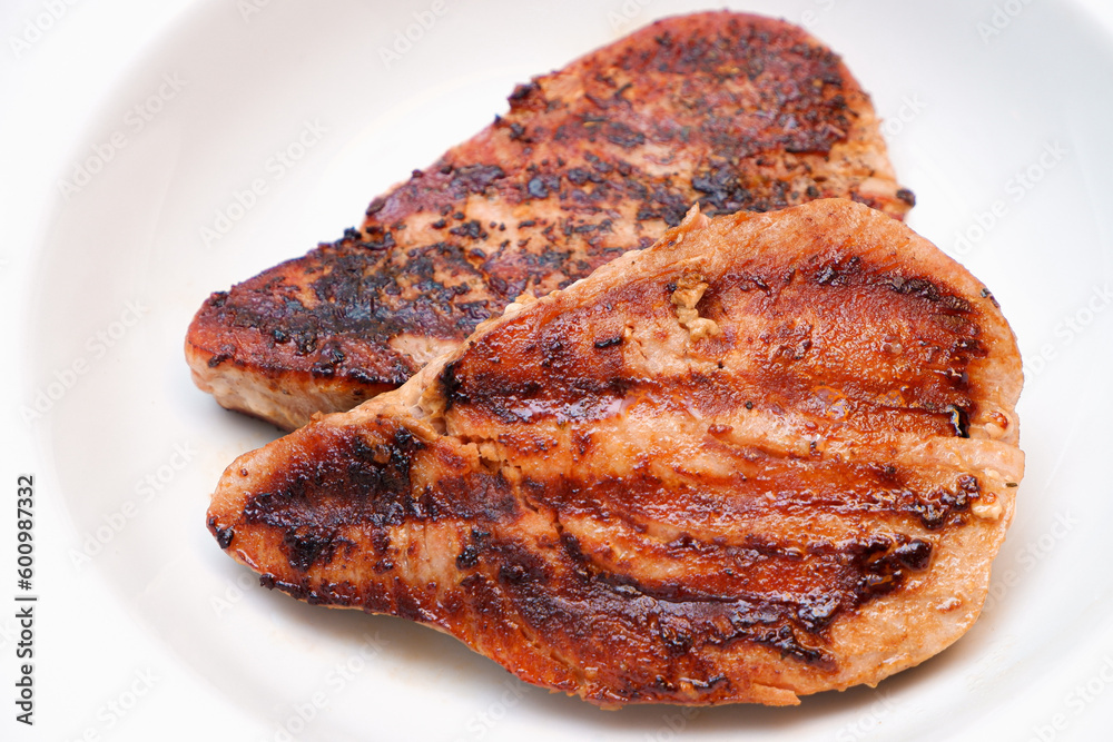 Grilled red tuna steak with pepper macro on a white plate. Grilled red tuna steak with pepper macro on a white plate.