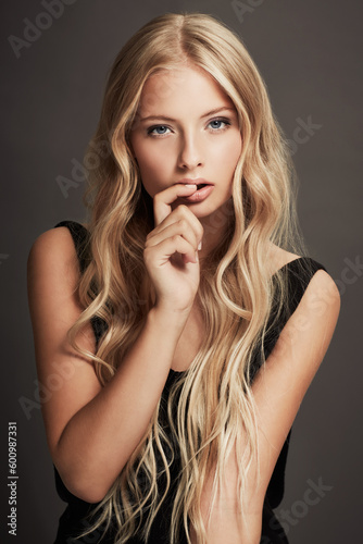 Beauty, face and portrait of a seductive woman with makeup, cosmetics and long hair in studio. Sexy female aesthetic model with skin glow, luxury skincare and finger in mouth on a grey background