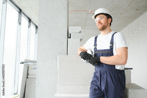 Fotografia, Obraz Portrait of positive, handsome young male builder in hard hat.