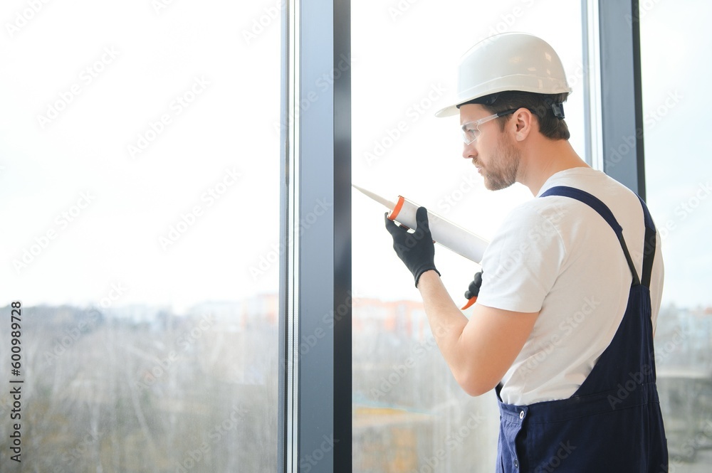 Construction worker installing window in house. Construction worker installing window in house.