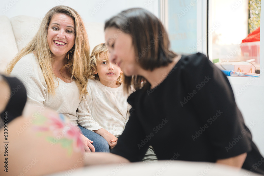 Woman with her child watching her pregnant wife's belly being painted. Concept of motherhood, pride, integration, assisted reproduction. Woman with her child watching her pregnant wife's belly being painted. Concept of motherhood, pride, integration, assisted reproduction.