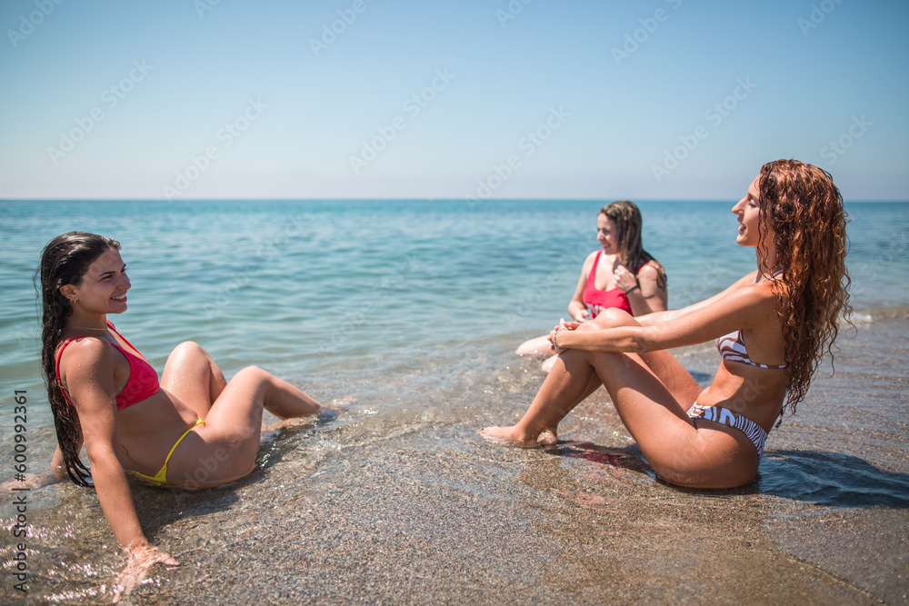 Women chatting relaxed while sitting on the beach