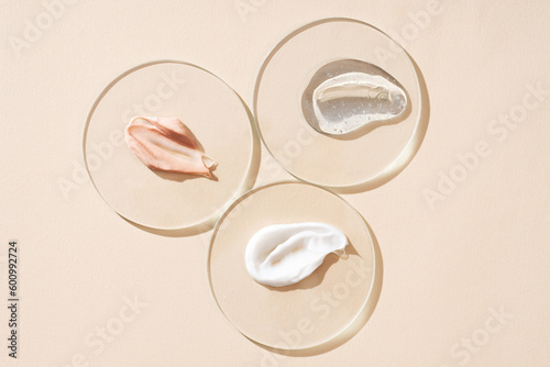 Cosmetic background, smears of cream on glass, texture of cream on a pastel beige background.