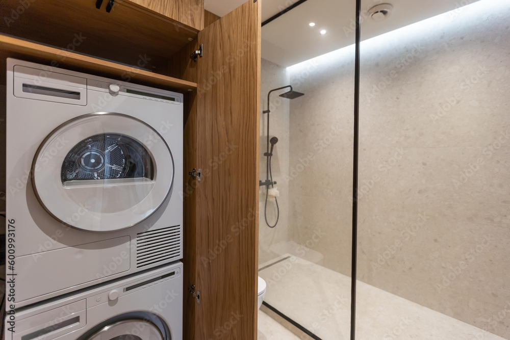Marble laundry room interior with wooden countertops, a closet and built in washing machines Marble laundry room interior with wooden countertops, a closet and built in washing machines
