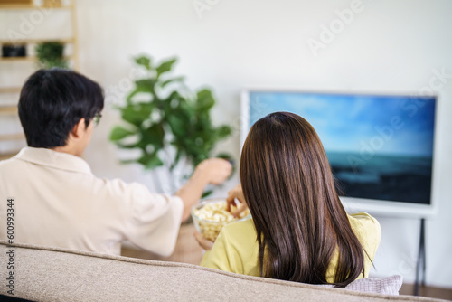 Asian family Watching smart TV together and using remote controller Hand holding popcorn at home with the remote control movie or TV series spending time at home