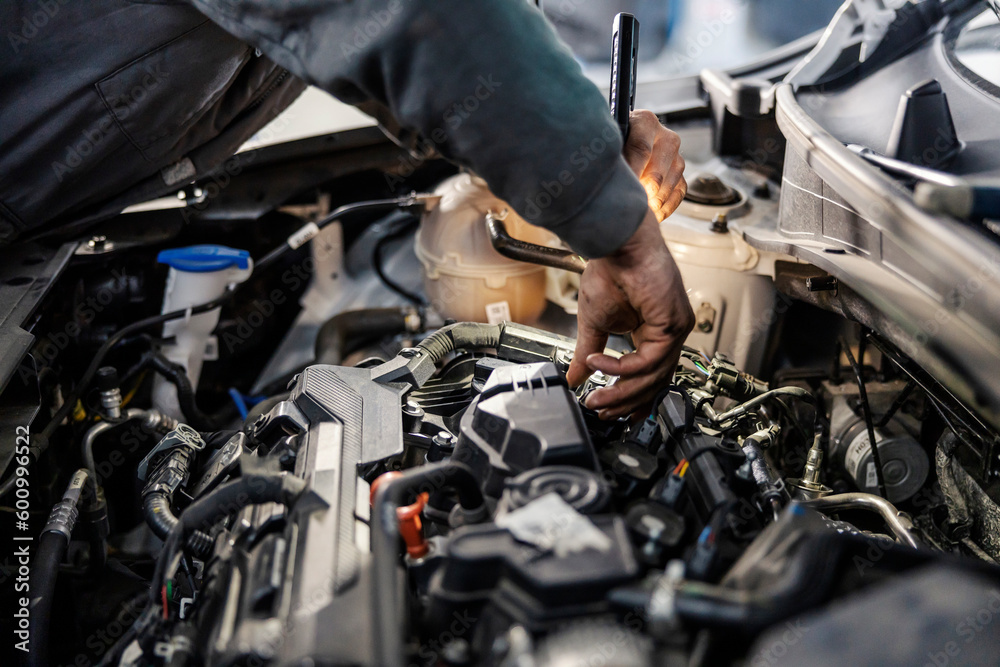 Close up of a mechanic doing car checkup with flashlight at mechanic's workshop. Close up of a mechanic doing car checkup with flashlight at mechanic's workshop.