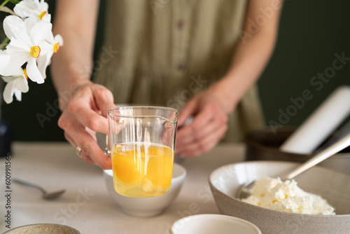 Holding a bowl of eggs to beat. Woman preparing cheesecake at home