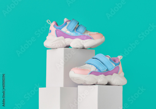 Baby sneakers, child sport shoes pair on color background. Fashion kids outfit. Fashionable sports shoes. Modern minimalistic layout with footwear mock up for your design. Advertising for shoe store
