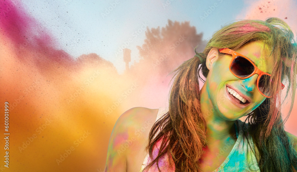 Carefree cheerful woman covered in rainbow colored powder celebrating the festival of colors. Young woman having fun with colorful holi powder outdoors Carefree cheerful woman covered in rainbow colored powder celebrating the festival of colors. Young woman having fun with colorful holi powder outdoors
