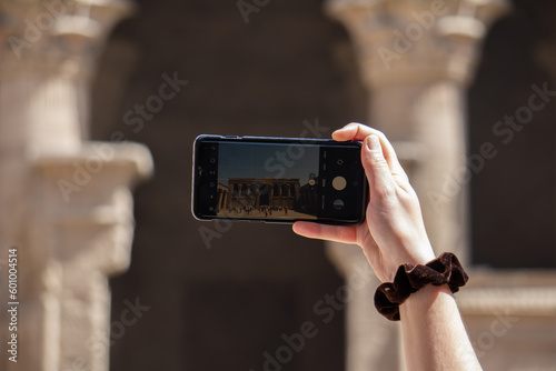Mano di una ragazza che fotografa un tempio egizio con il suo cellulare photo