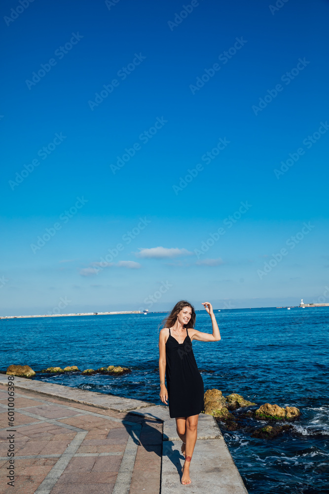 a woman walks along a pier near the sea walking the beach