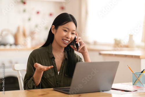 Beautiful chinese lady have phone conversation with client, kitchen interior