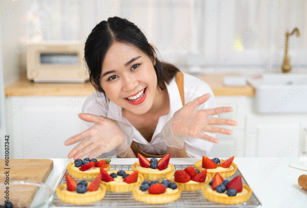 Asian woman bakery shop owner making bakery in the kitchen. Woman bakery chef making fruit tart with cream cheese on kitchen counter. Small business entrepreneur cafe and restaurant concept. Asian woman bakery shop owner making bakery in the kitchen. Woman bakery chef making fruit tart with cream cheese on kitchen counter. Small business entrepreneur cafe and restaurant concept.