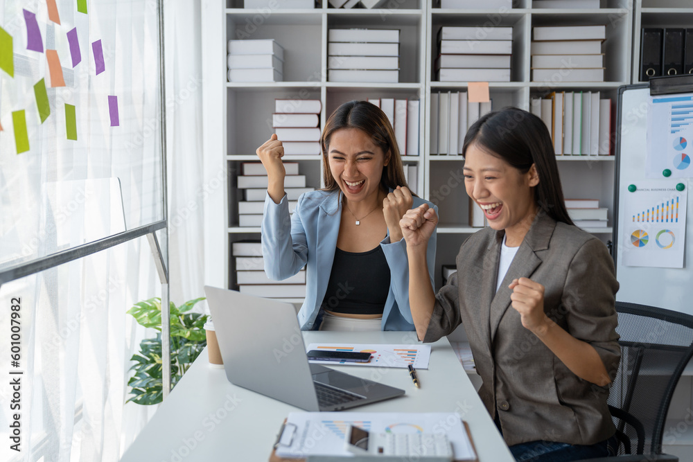 Two beautiful business women smiling happily and showing happy gestures in business. Finance. Investment approved with acceptance documents and laptop computer in office. Two beautiful business women smiling happily and showing happy gestures in business. Finance. Investment approved with acceptance documents and laptop computer in office.
