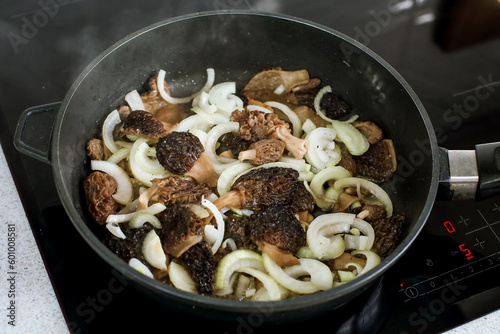 spring morel mushrooms with onions are fried in a frying pan