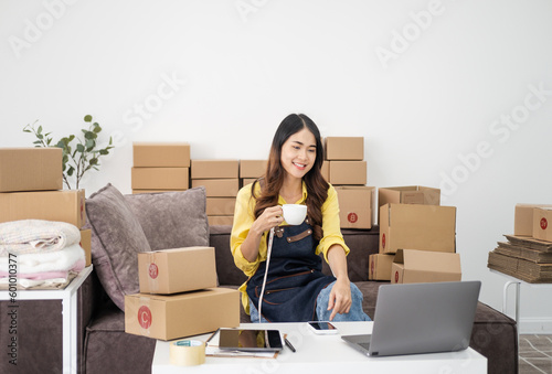 Young Women drinking coffee happy after new order from customer, business owner working at home office packaging on background. online shopping SME entrepreneur or freelance working concept.