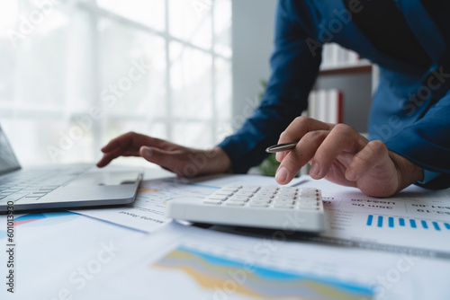 Confident businessman analyzing Calculate and view chart data from documents. financial report graph from laptop computer on office desk.