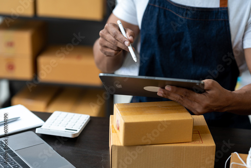 Freelance businessman checking and verifying shipping information Package boxes to prepare for delivery to customers who order online on laptop computers and tablets. ecommerce startup business ideas © crizzystudio