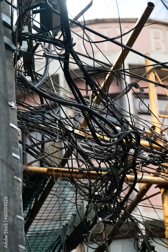 Close up shot of a tangle of cables and electricity wires tied on a pole in Binondo, Manila's Chinatown. Mess and chaos in the telephone lines. Typical asian metropolis view.