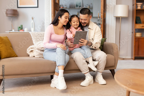 Japanese Parents And Child Using Digital Tablet Browsing Internet Indoor