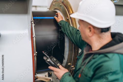 Inspector is measuring thickness of the pipe material from near to weld with a portable ultrasonic wall thickness measurement gauge. It is a method of performing non destructive measurement .