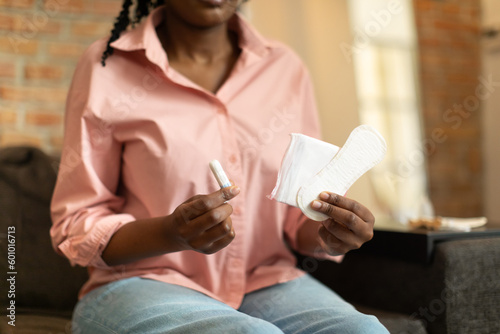 Female period and intimate hygiene. Young black woman holding tampon vs clean menstrual pads