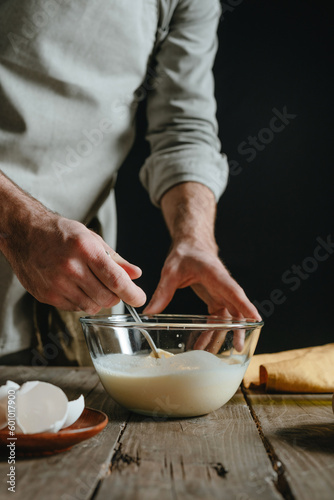 Unrecognizable man in an apron mixing dough ingredients